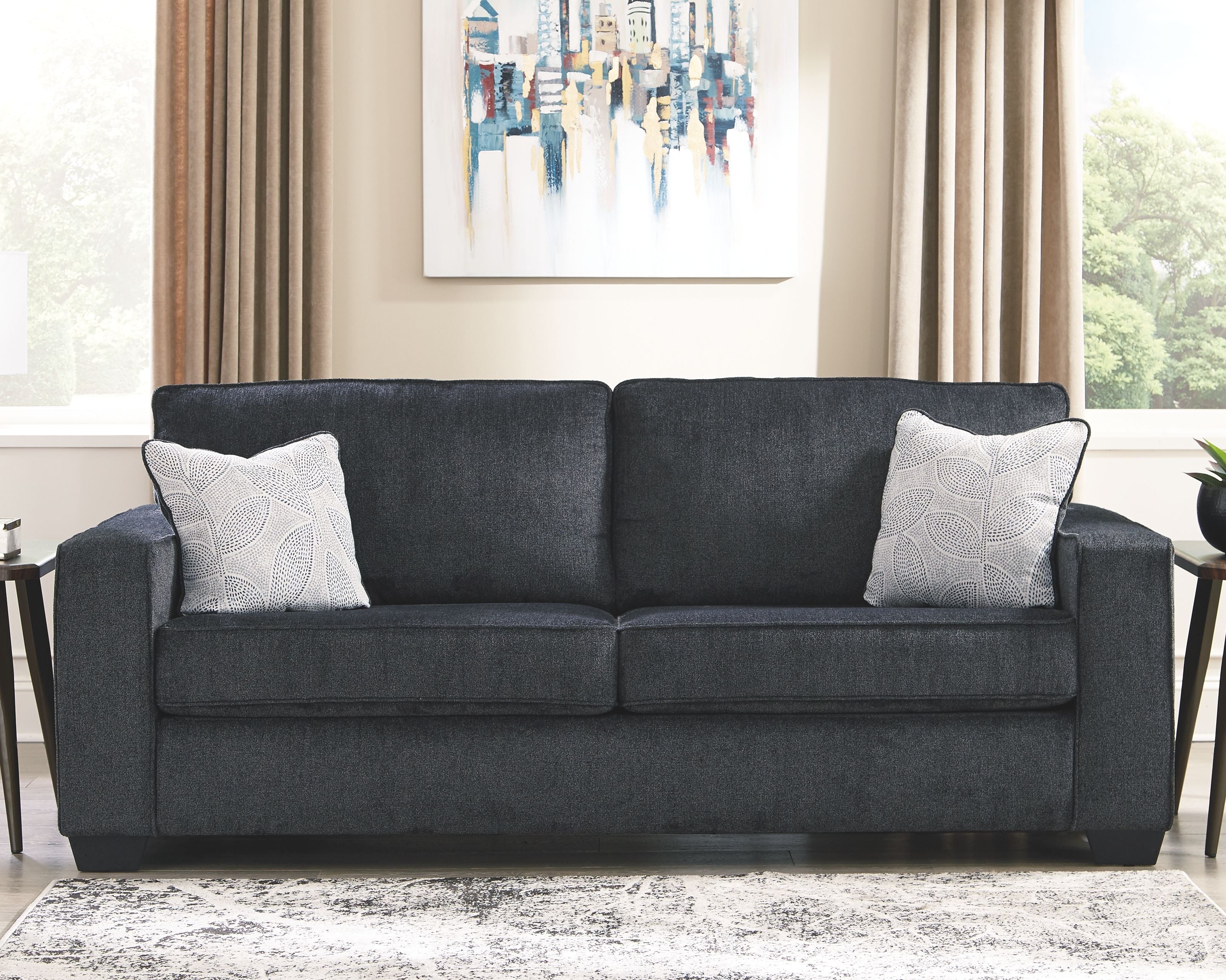 Slate sleeper sofa styled in a living room with two patterned throw pillows