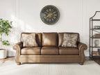 Chasemore sofa in tan with two patterned accent pillows and turned wooden legs