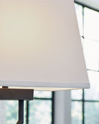 Black metal table lamp with white fabric shade and brushed base edge