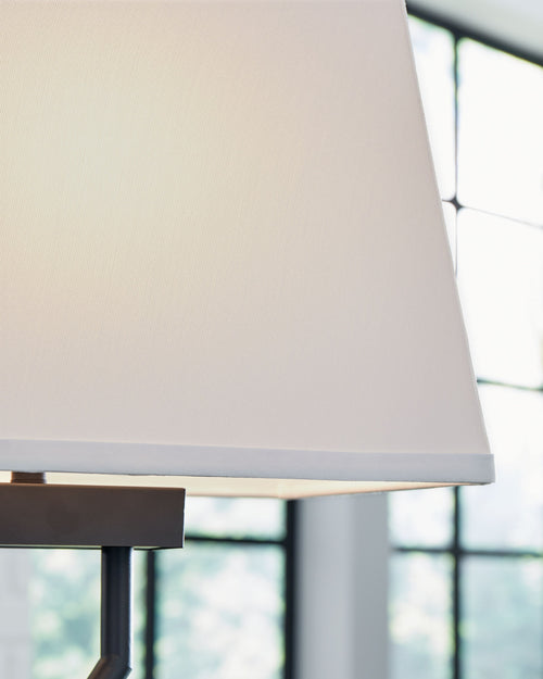 Black metal table lamp with white fabric shade and brushed base edge