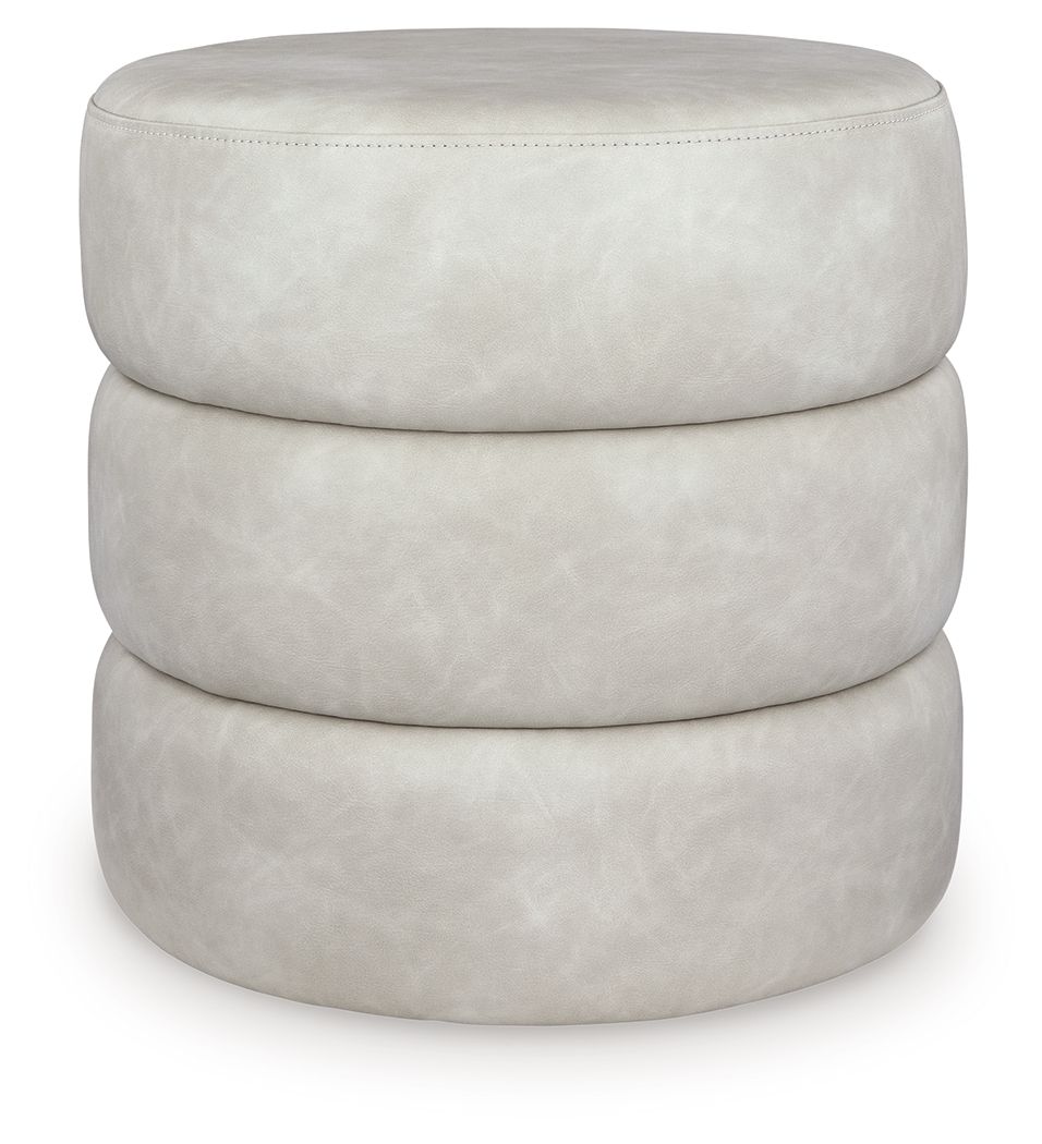 White upholstered swivel ottoman with round top, layered base, and fabric seam stitching.