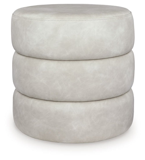 White upholstered swivel ottoman with round top, layered base, and fabric seam stitching.