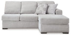 Light gray chaise sofa section with tufted back cushions and patterned throw pillow