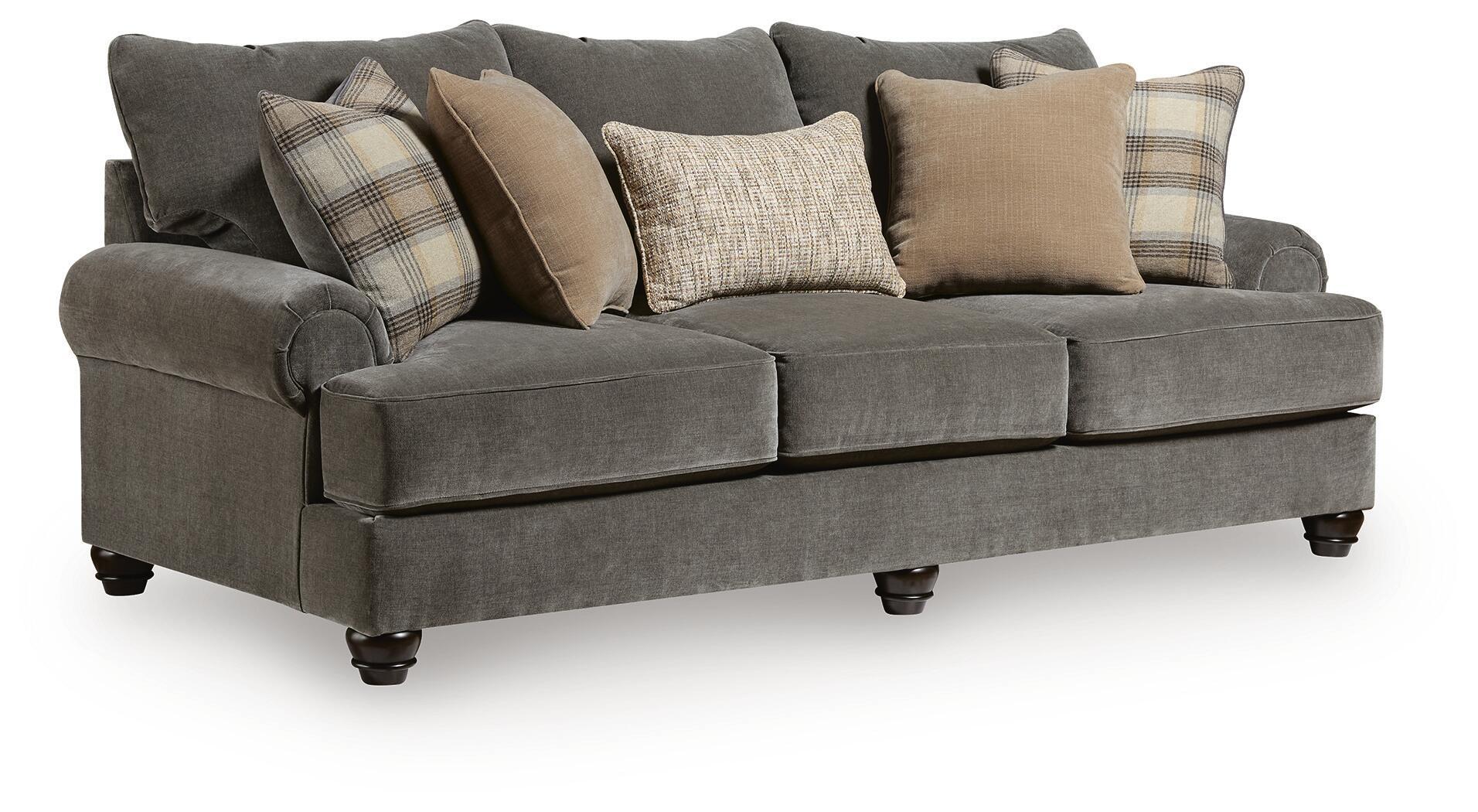 Gray upholstered sofa with tufted arms and mix of plaid and tan throw pillows