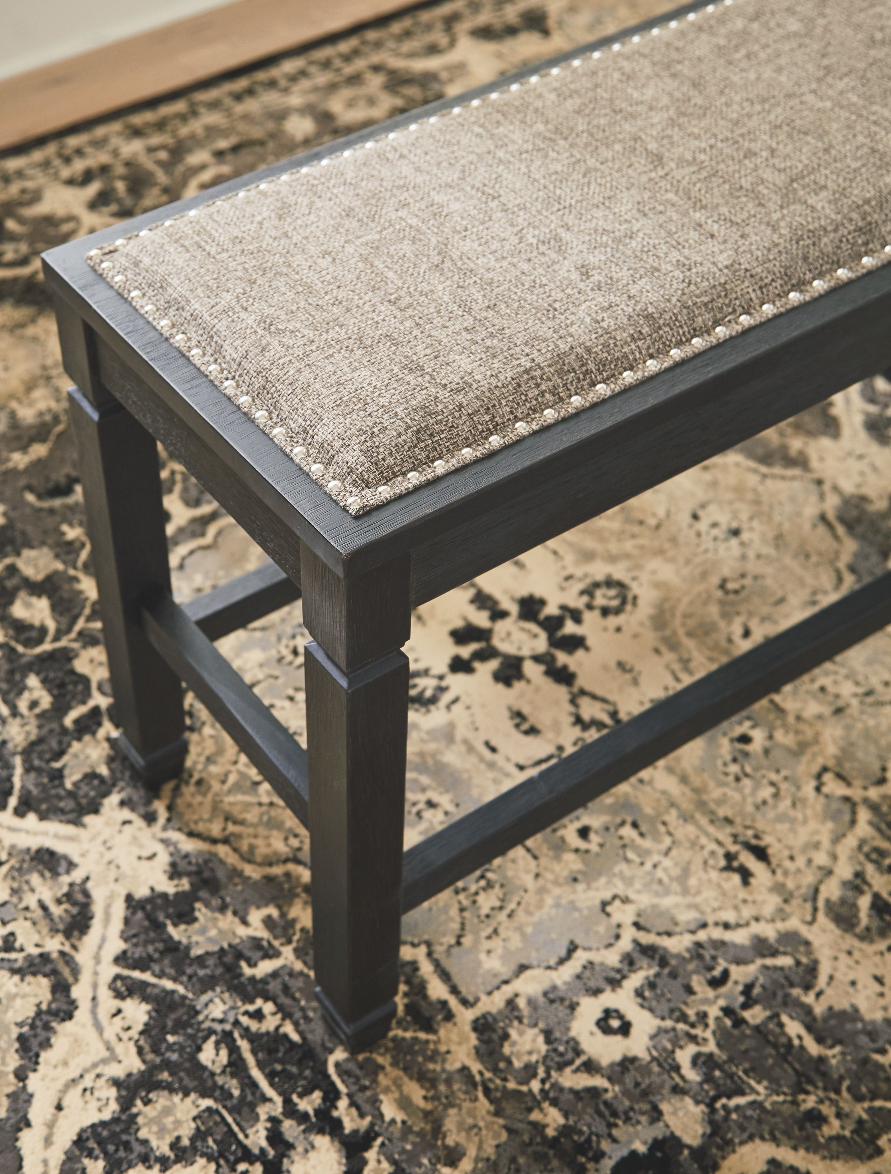 Upholstered bench with dark wood frame and textured light seat cushion, angled view