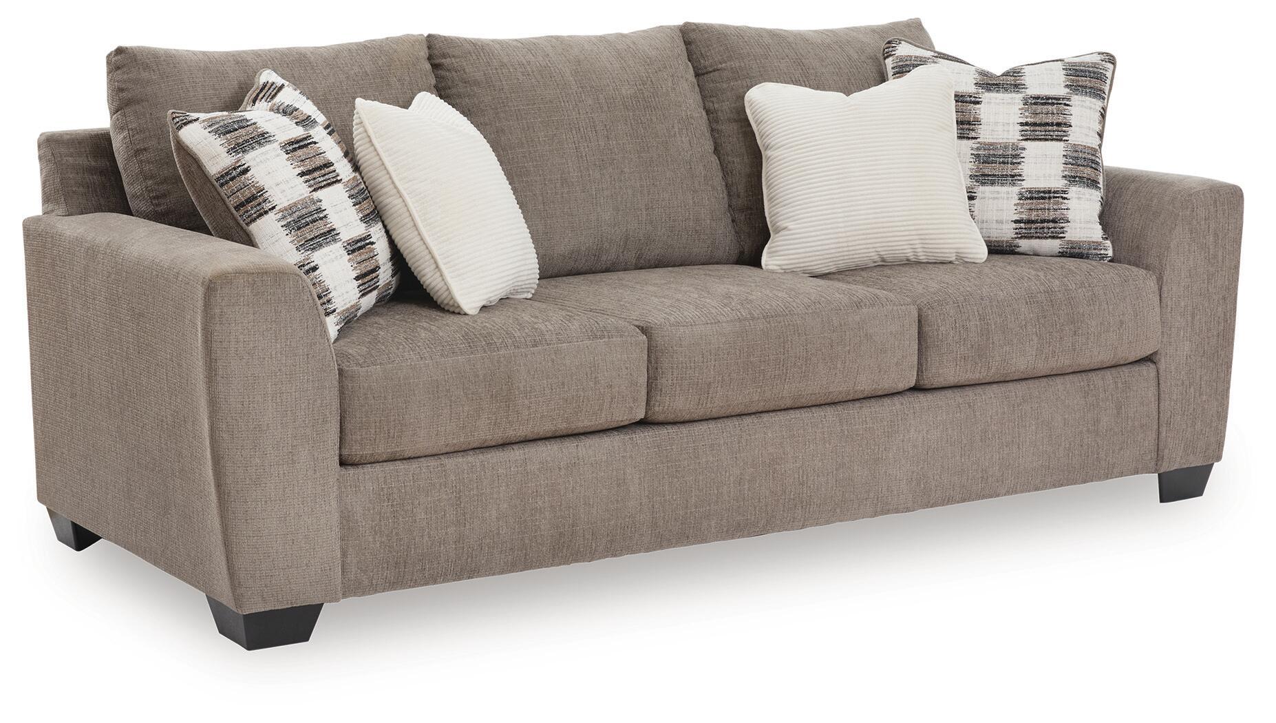 Sofa sleeper, tan upholstery with plaid and white throw pillows.