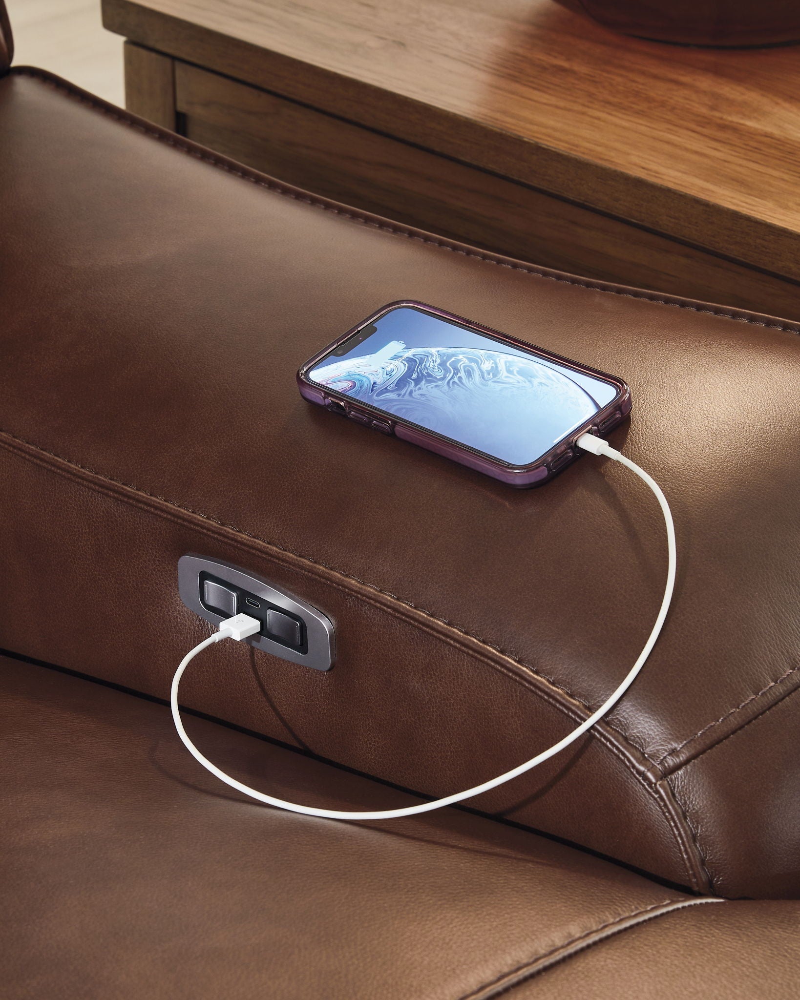 Sectional armrest charging panel with USB port and phone connected by cable