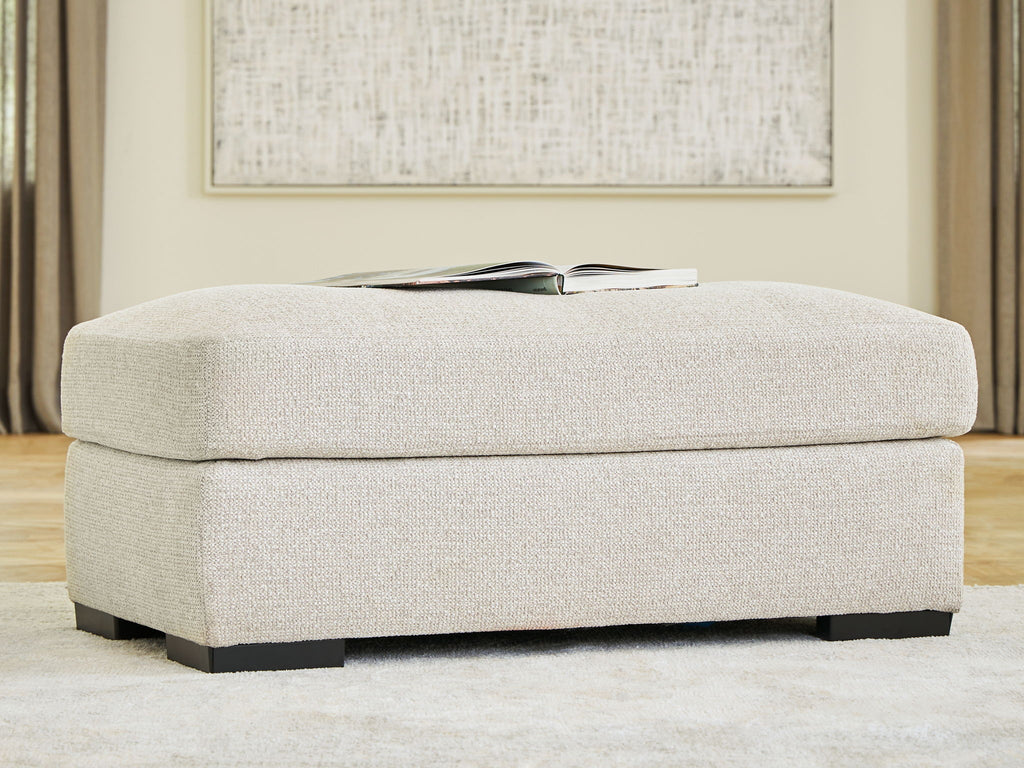 Upholstered ottoman with light beige linen fabric and low dark wood legs