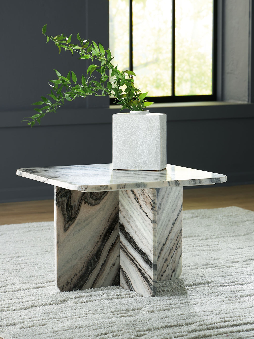 Accent cocktail table with veined white marble-look top and angled pedestal base