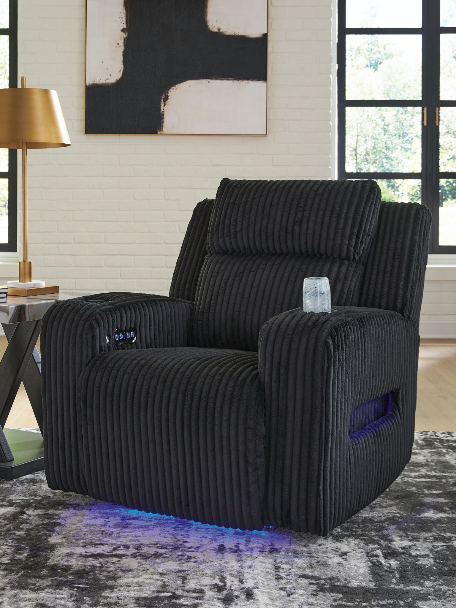Black corduroy recliner with adjustable headrest and wide cushioned seat