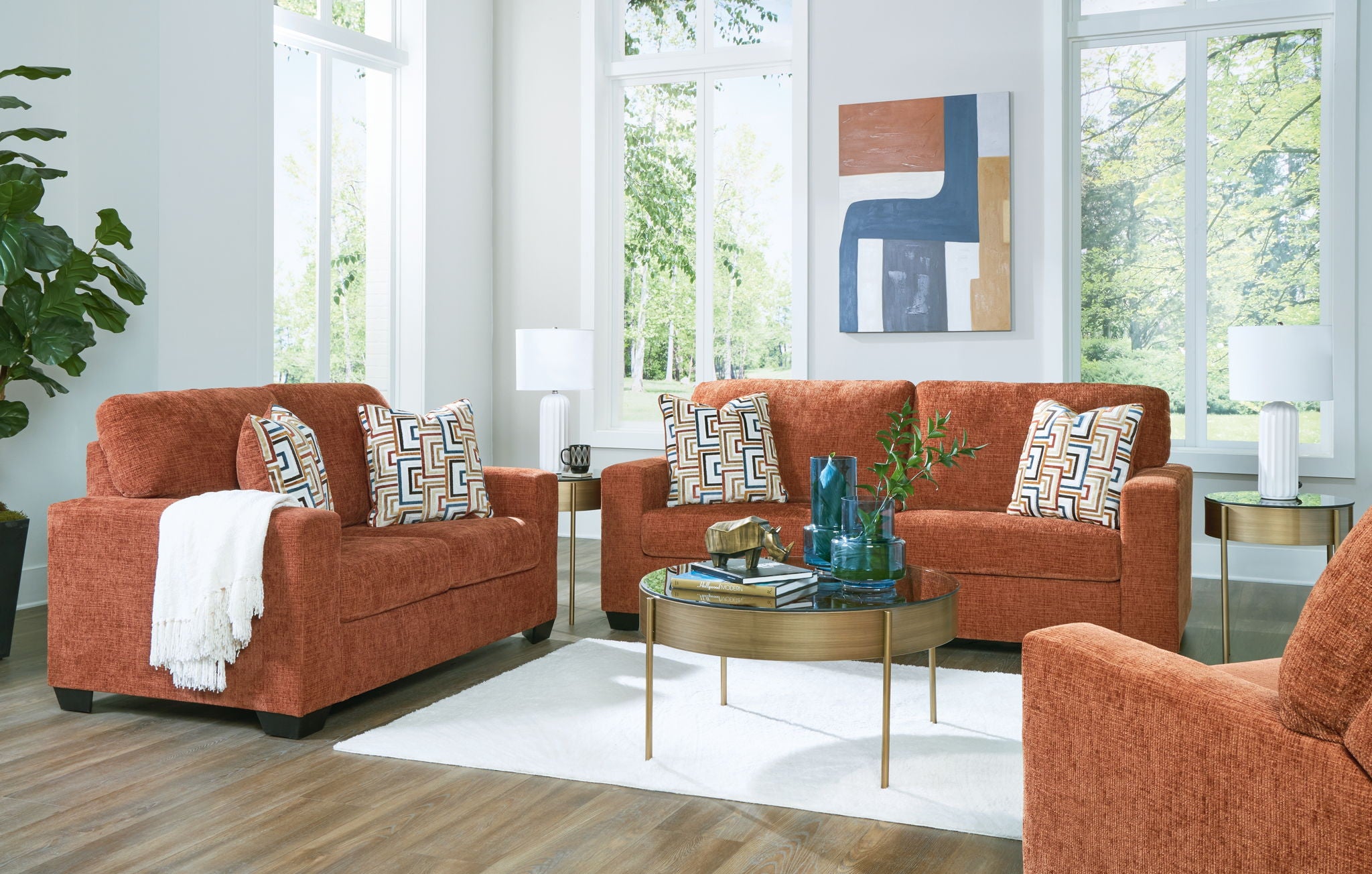 Terracotta sofa and loveseat with patterned pillows and accent chair