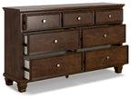 Brown dresser with several drawers and round knobs, raised panel trim