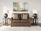 Brown loveseat with two patterned throw pillows and rolled arms