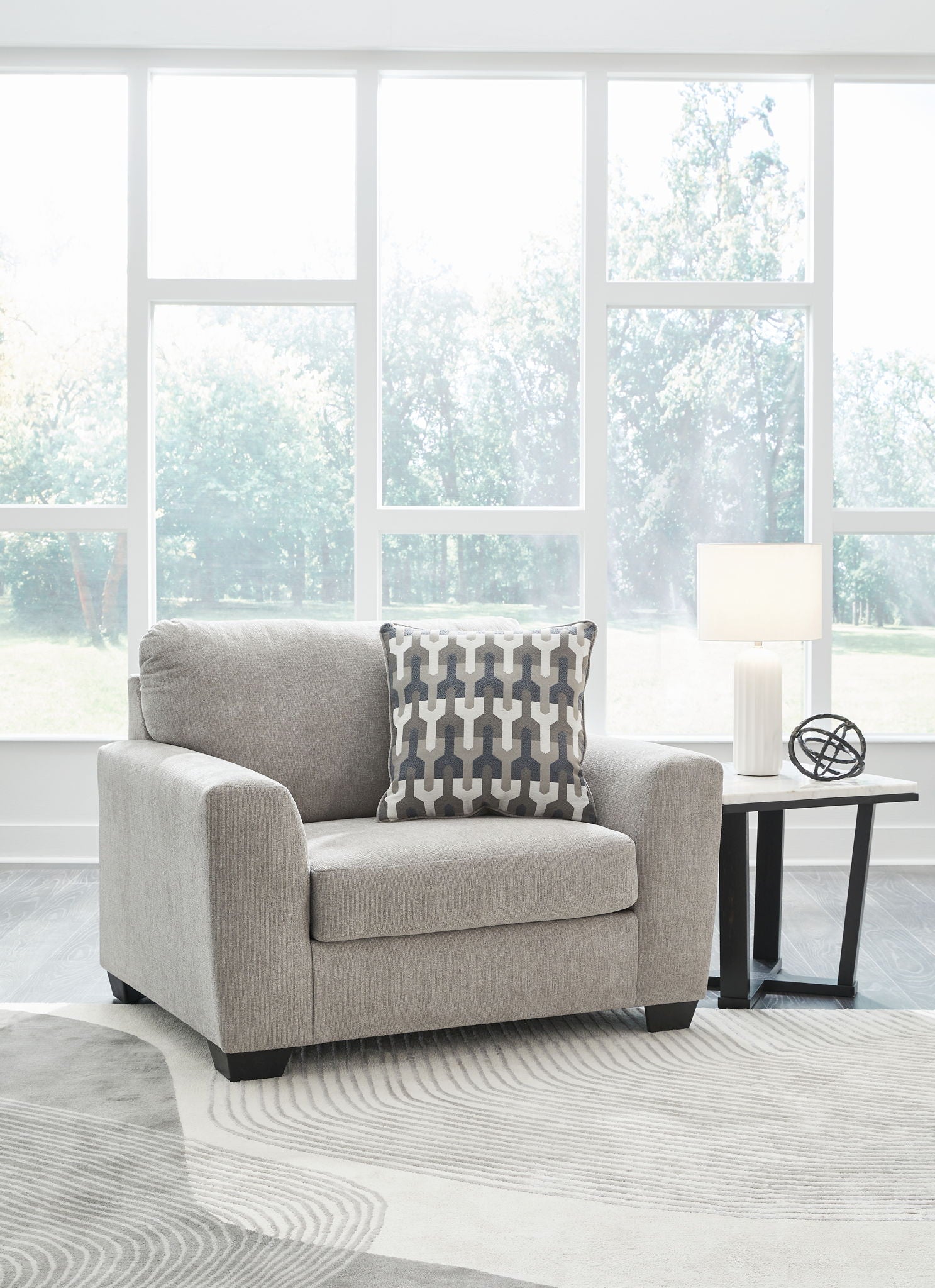 Gray upholstered armchair with patterned lumbar pillow and solid throw pillow