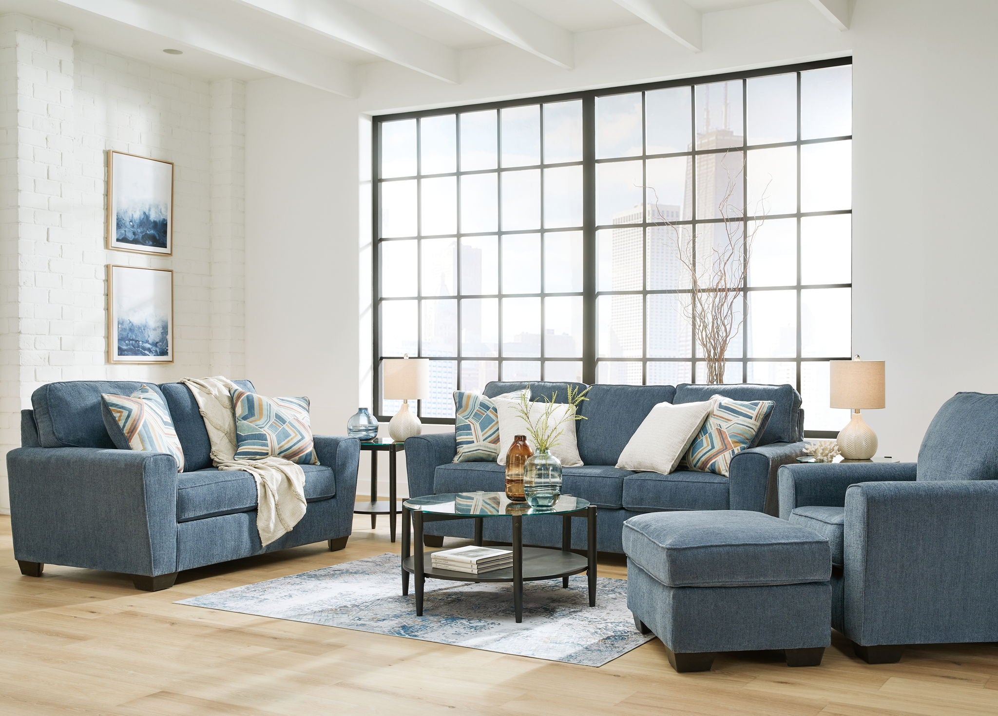 Blue fabric living room set with sofas, ottoman, and patterned accent pillows