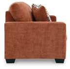 Spice rust sofa sleeper with arm and back cushions, plus patterned throw pillow.
