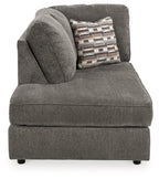 Gray corner chaise with curved back cushion and patterned throw pillow