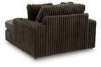 Oversized chaise with ribbed dark fabric, rounded arm blocks and layered back pillows.