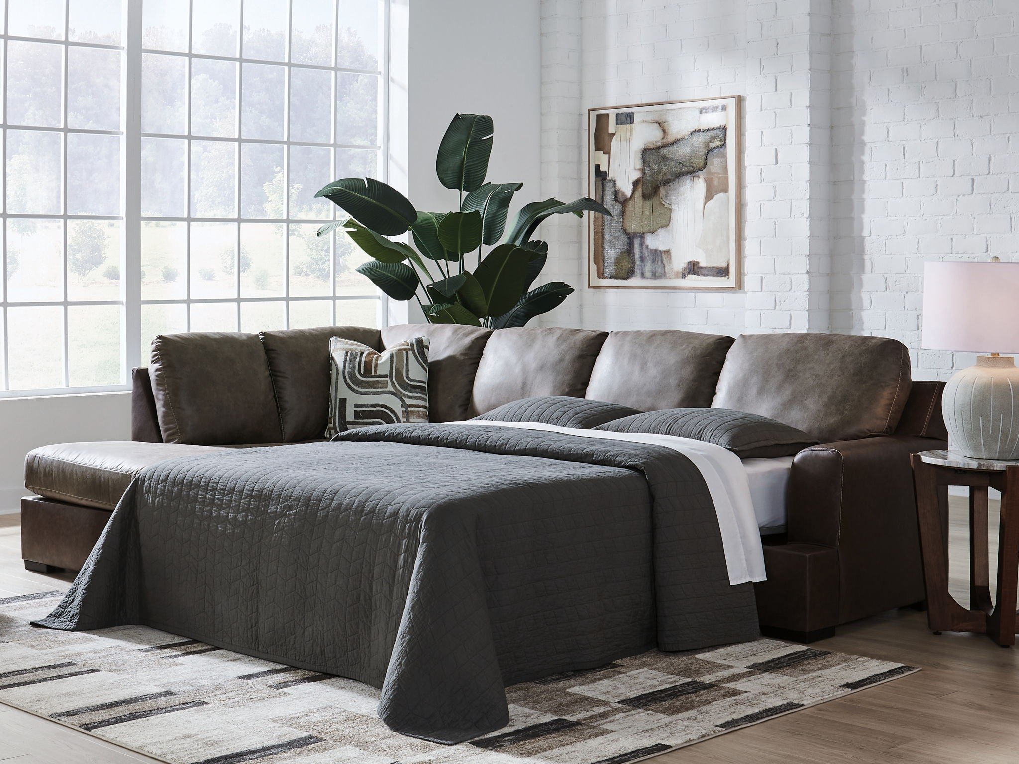 Dark fossil sectional sofa with chaise and gray pillows plus draped throw blanket