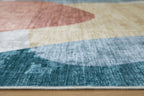 Blue washable rug with abstract geometric blocks in beige, coral, and light gray