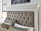 Tufted taupe upholstered headboard with nailhead trim and pillows