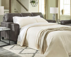 Dark gray sleeper sofa with mattress extended and bed side armrest