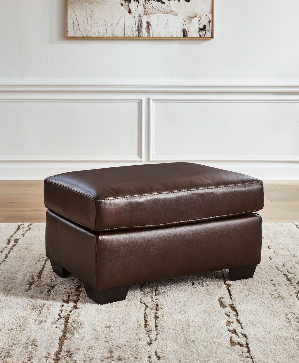 Dark brown ottoman with cushioned top and padded sides, shown with block feet
