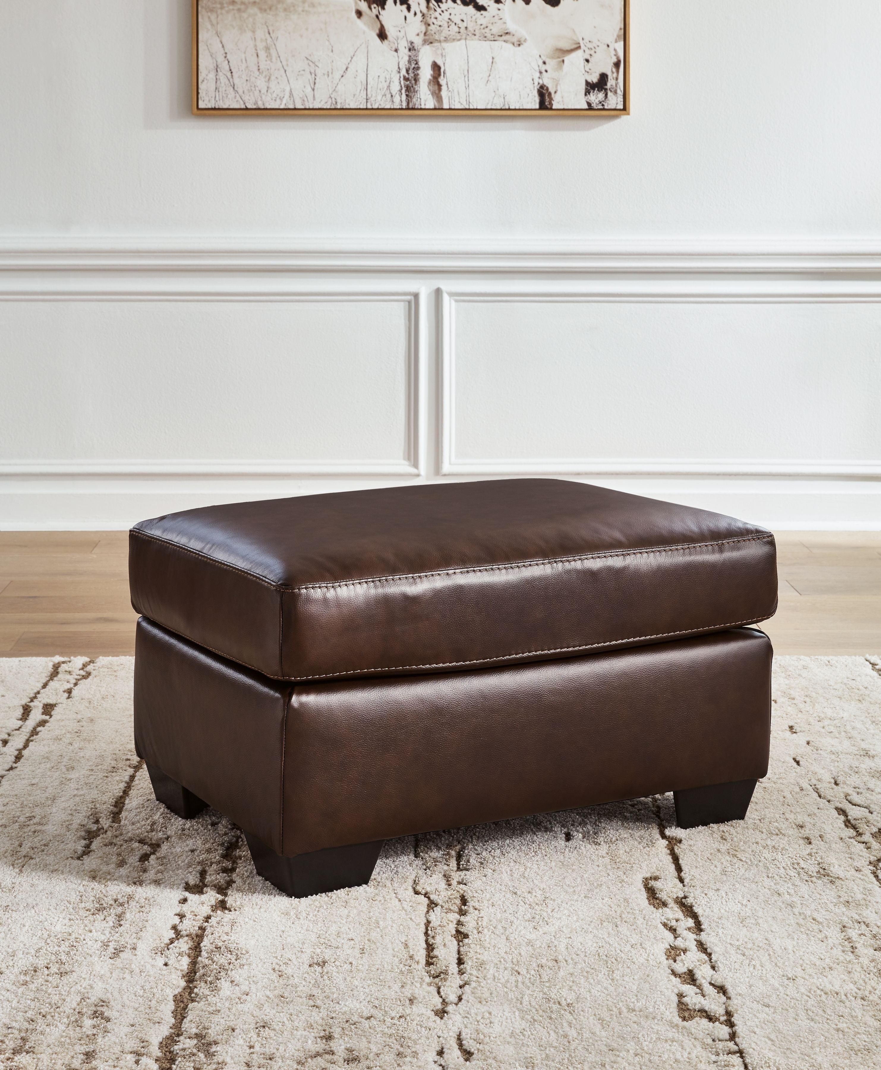 Dark brown ottoman with cushioned top and padded sides, shown with block feet