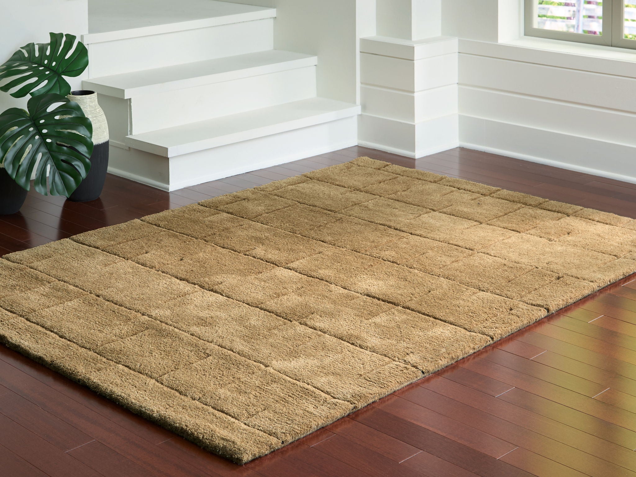 Light brown textured rug with rectangular block design and thin border