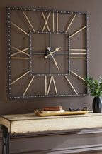 Square wall clock with black frame and gold hands, mounted on wall