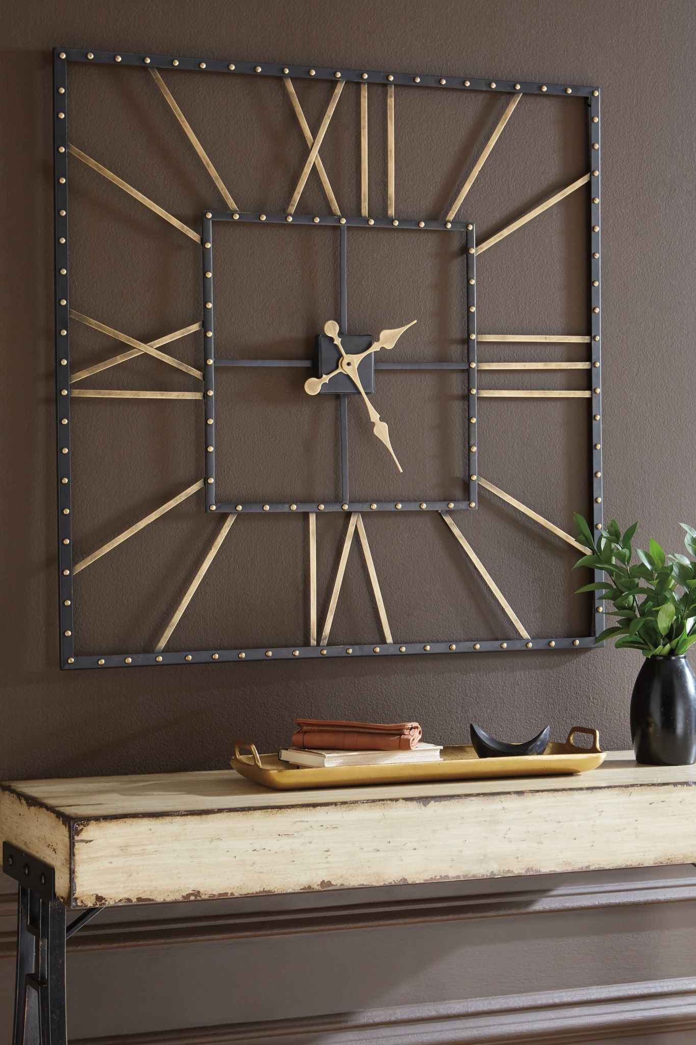 Square wall clock with black frame and gold hands, mounted on wall