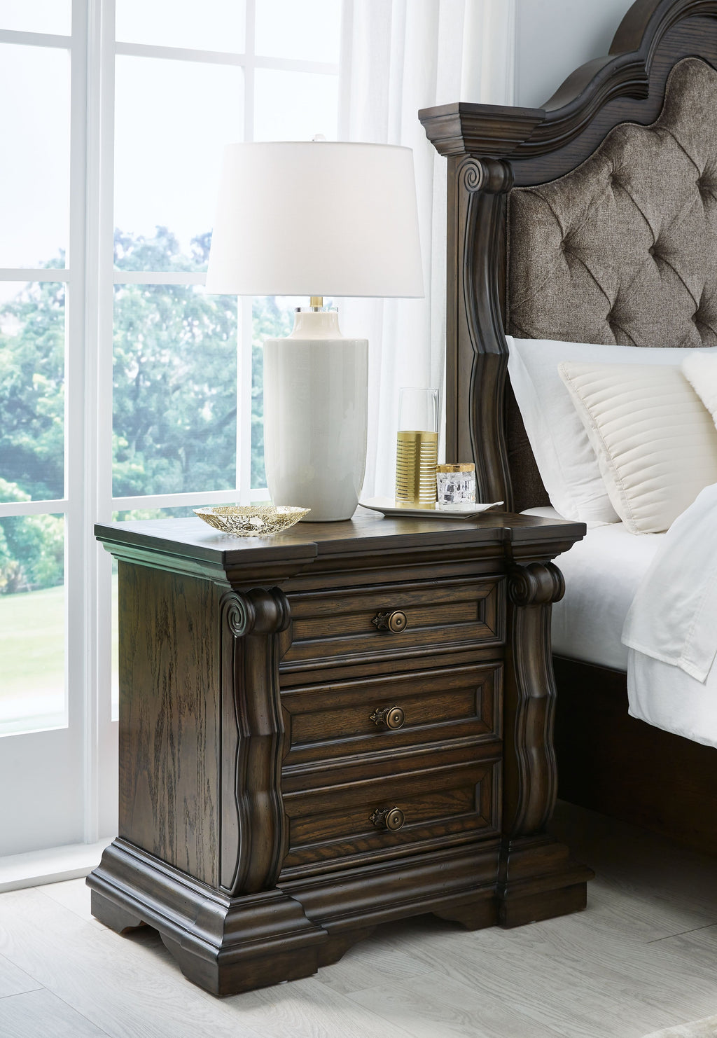 Dark brown three-drawer night stand with scalloped trim and round knob pulls