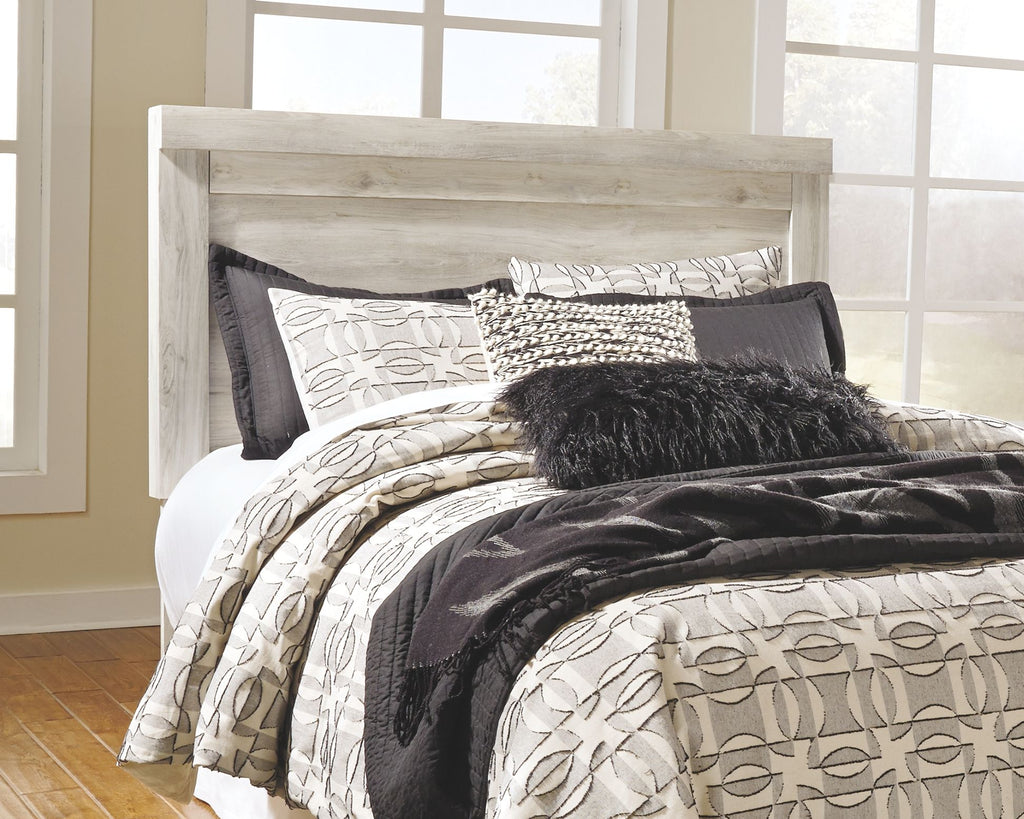 Beige panel headboard with bolt-on metal bed frame and layered pillows