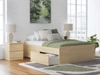 Light brown platform bed with storage drawers and green bedding
