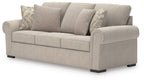 Heather fabric sofa in light beige with patterned and solid throw pillows, rounded armrests