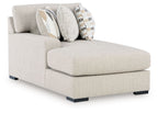 Light pebble fabric corner chaise with squared arms, black legs, and patterned throw pillows