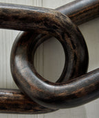 Dark chain sculpture with overlapping oval links and rustic finish