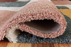 Pink shag-style rug edge with curled pile and gray backing