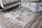 Dark gray distressed area rug with abstract pattern in a room corner
