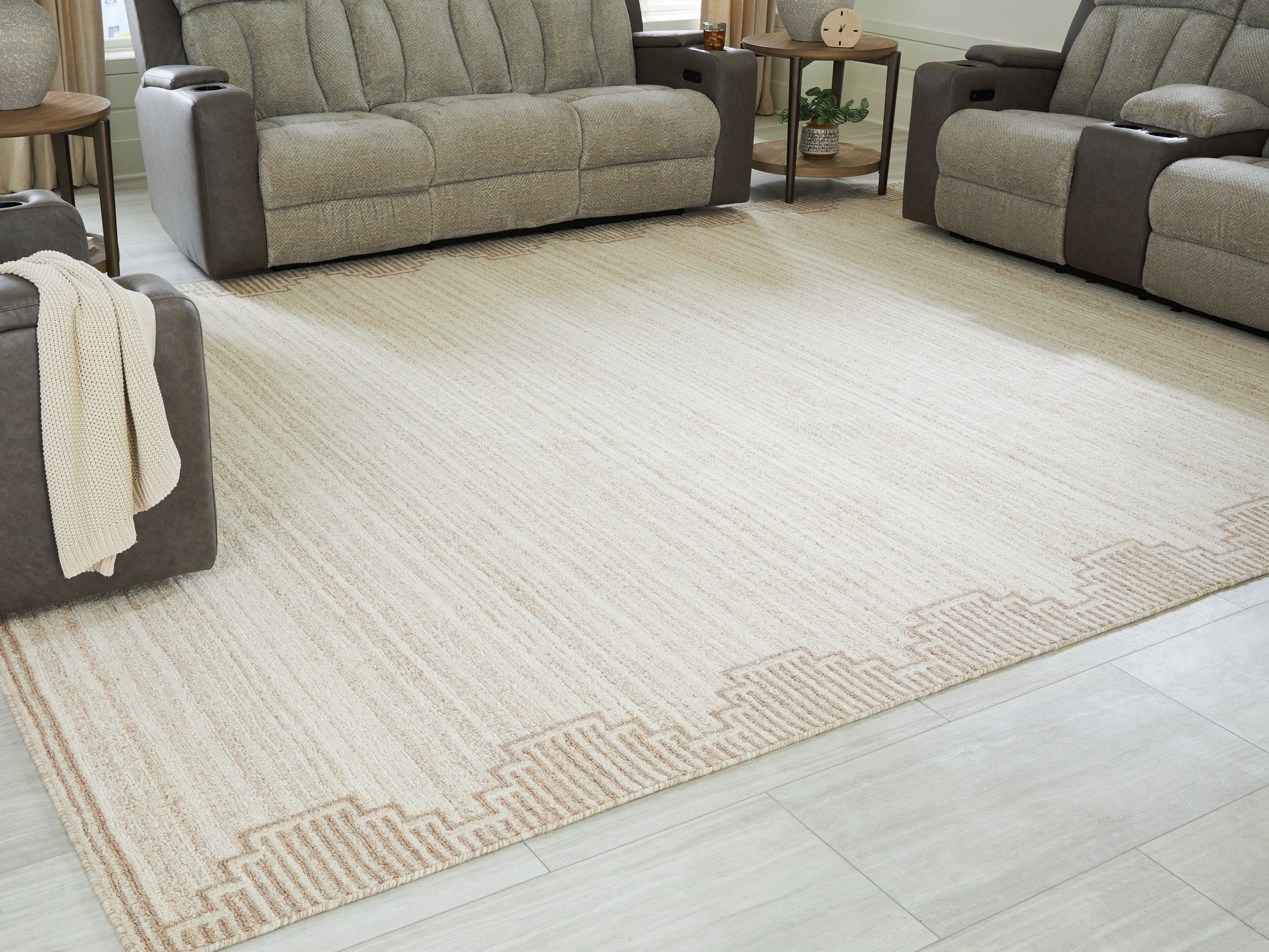 Beige living room rug with geometric border detail along the edge