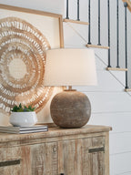Antique brown metal table lamp with white fabric shade and textured globe base