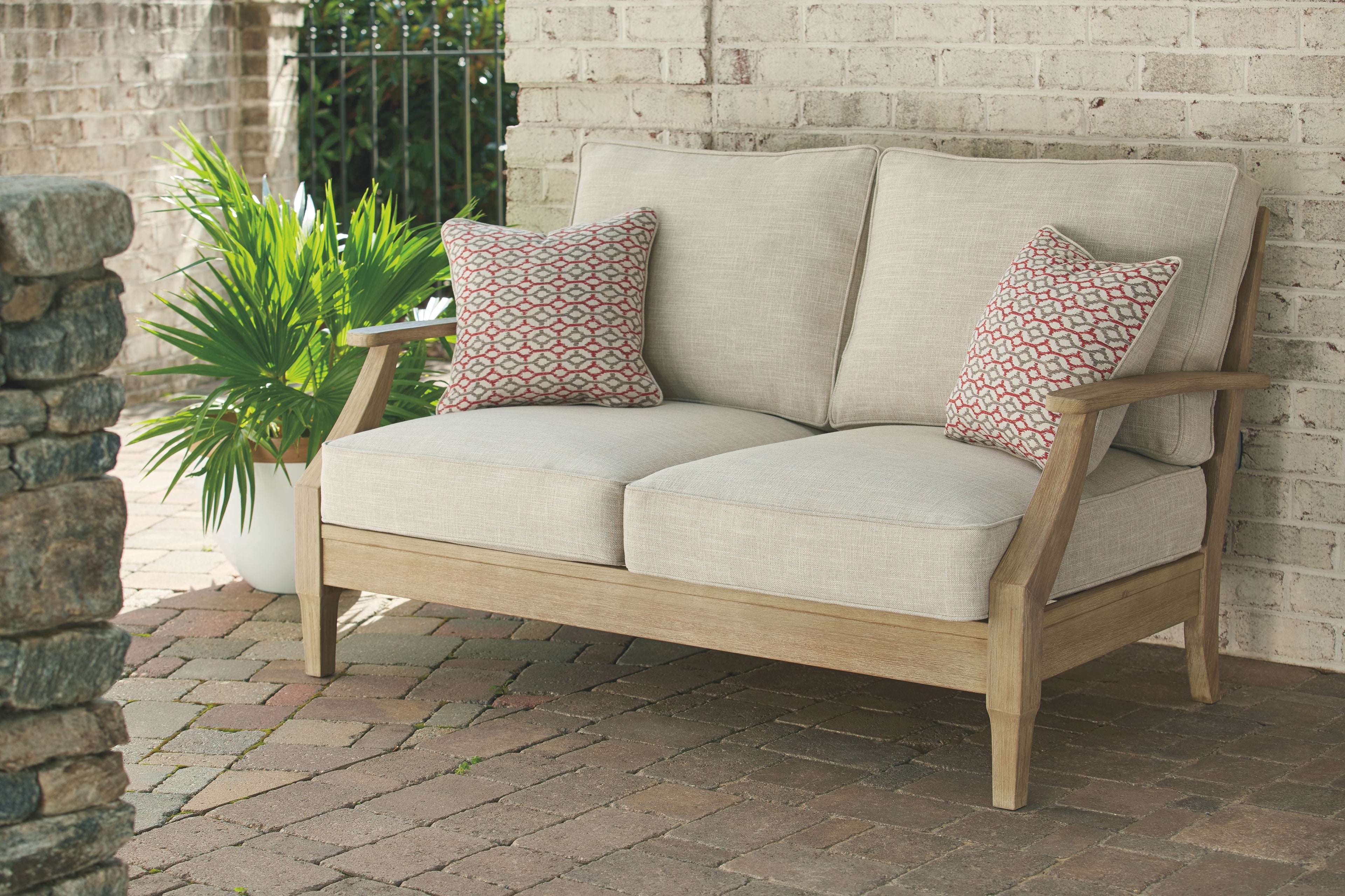 Beige loveseat with cushion and two patterned throw pillows