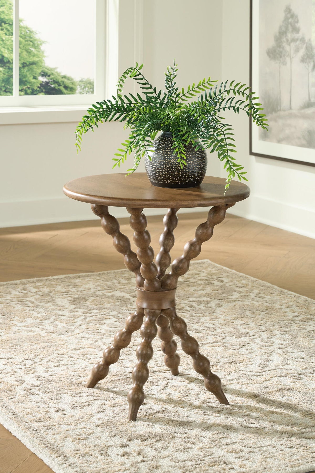 Round accent table with carved pedestal legs in a light brown finish