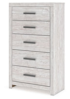 Whitewash five-drawer chest with dark bar pulls and visible side panel, angled view