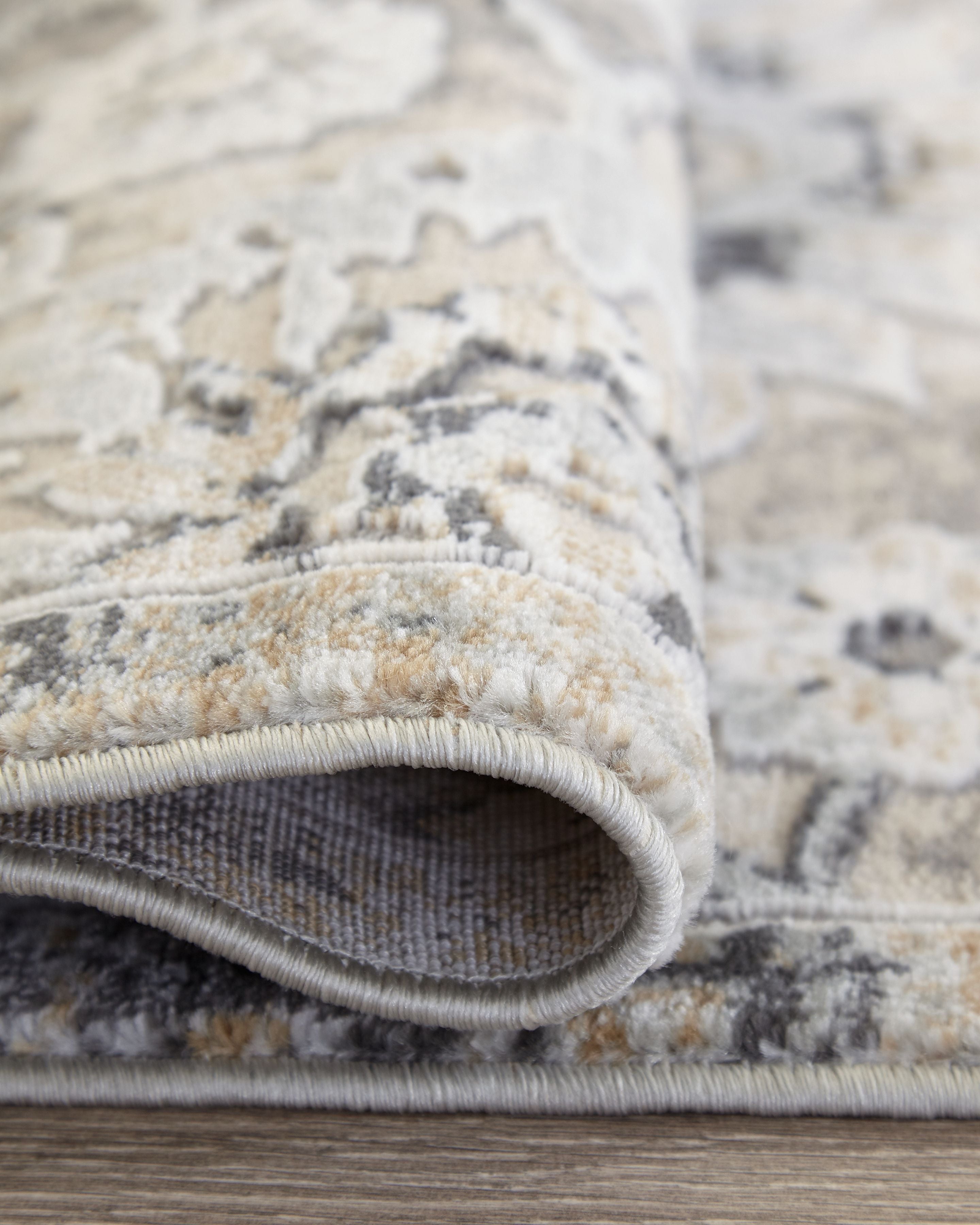 Gray and cream area rug border with stitched rolled edge