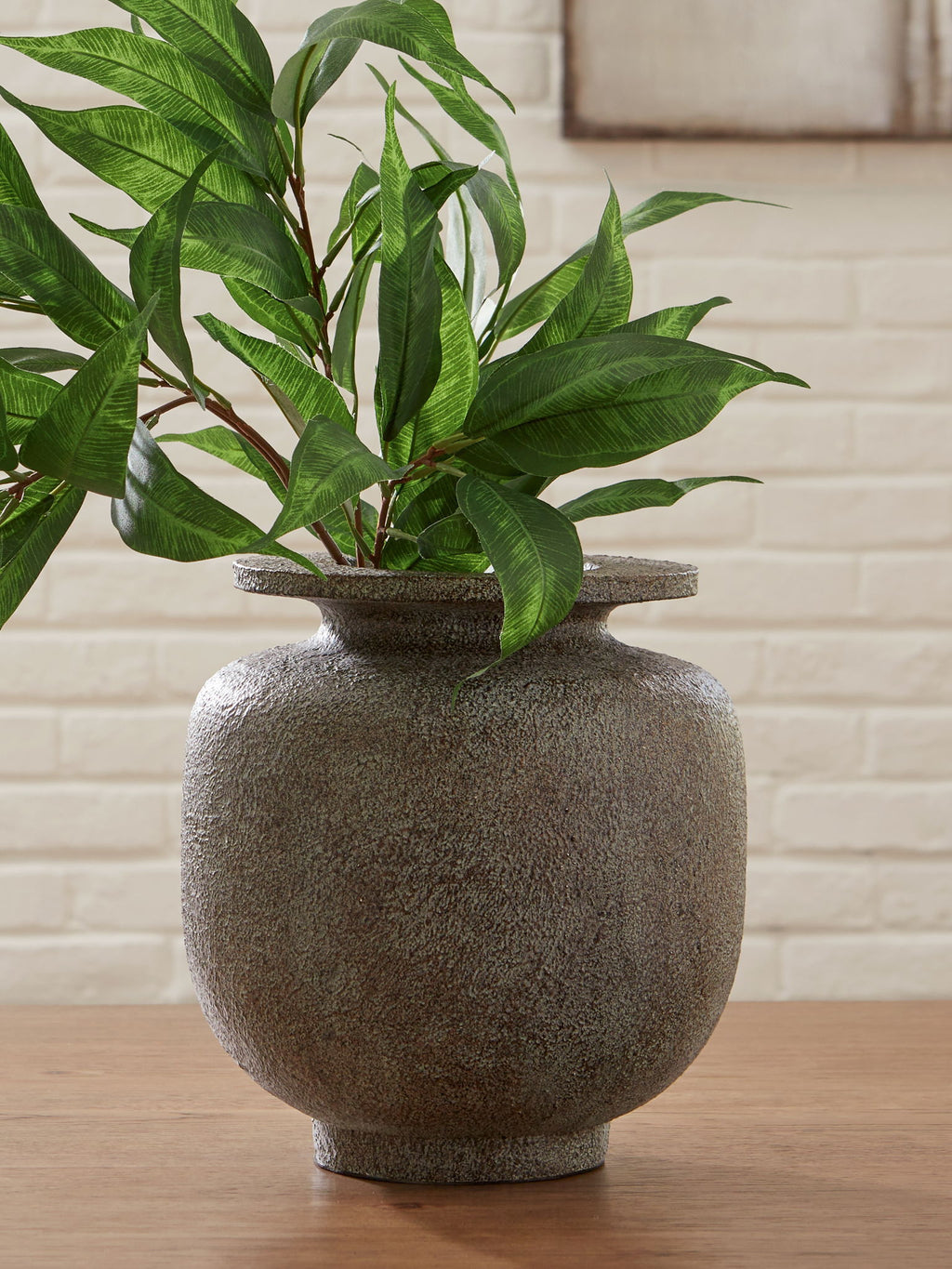Gray speckled vase holding green leafy stems