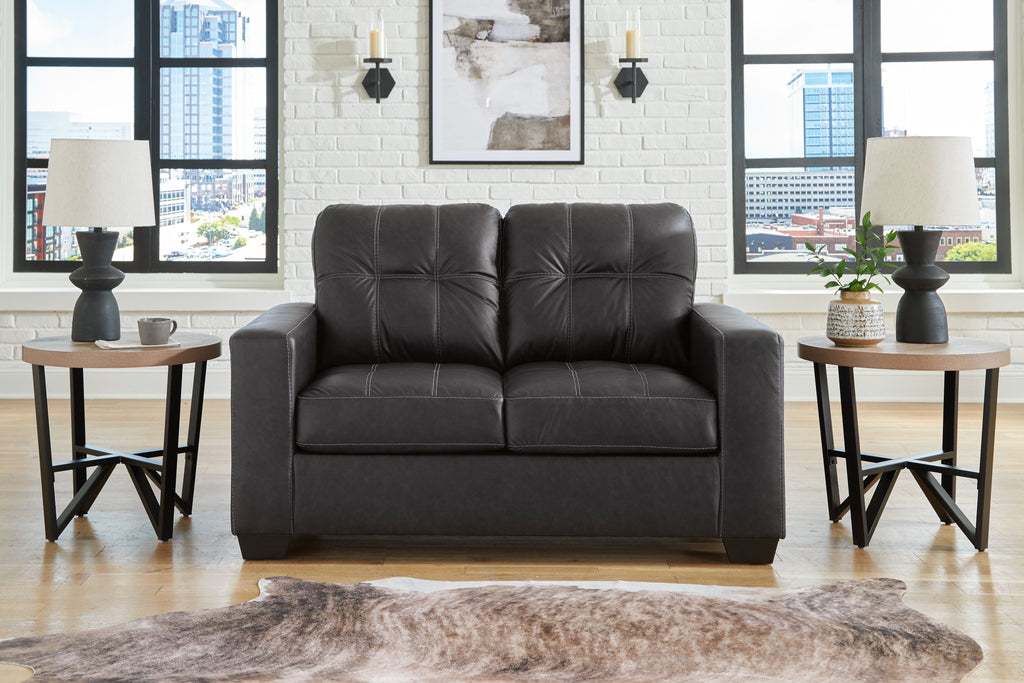 Black loveseat with tufted back, two-seat cushions, and padded armrests