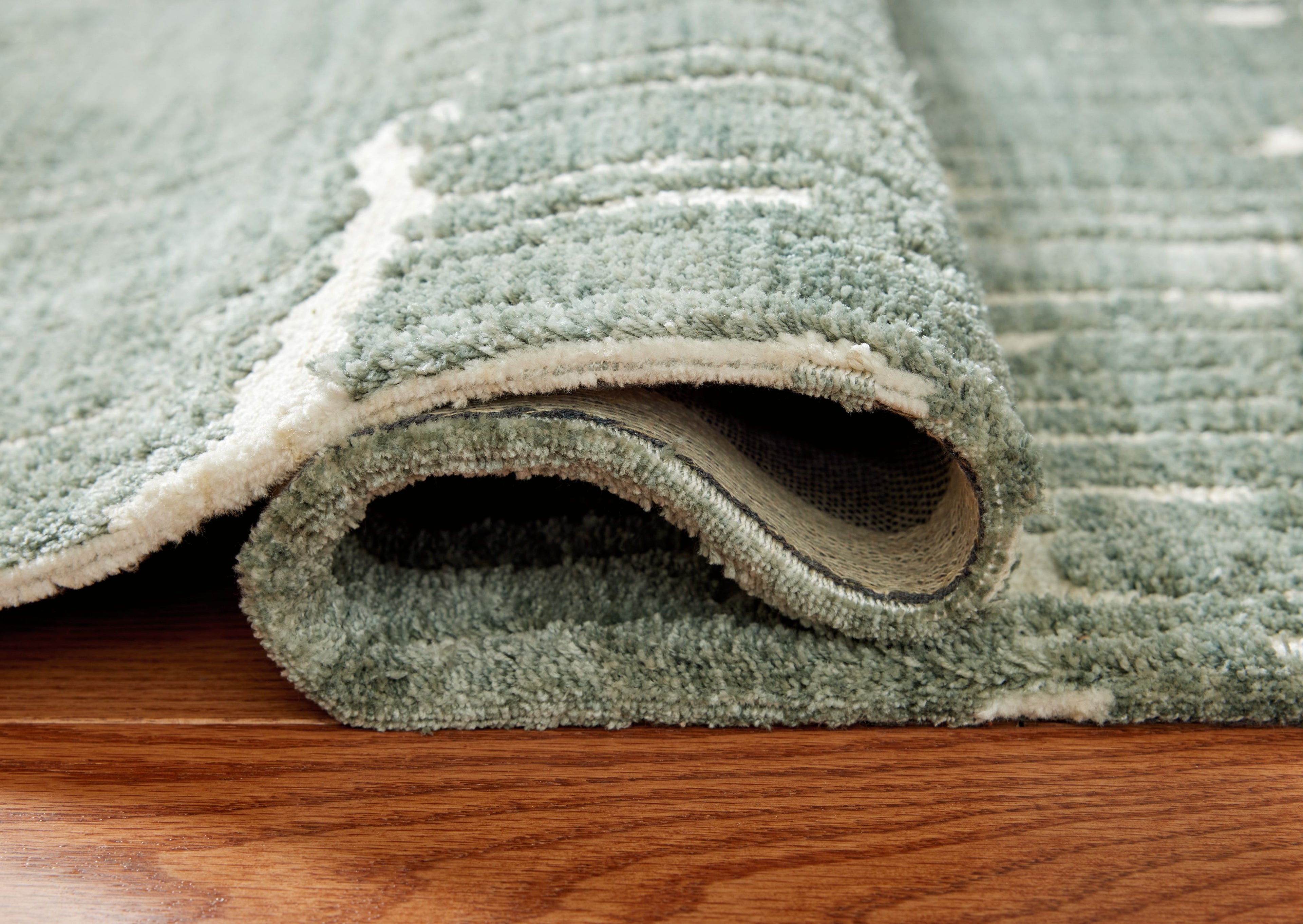 Light blue area rug showing thick low-pile texture and rolled edge