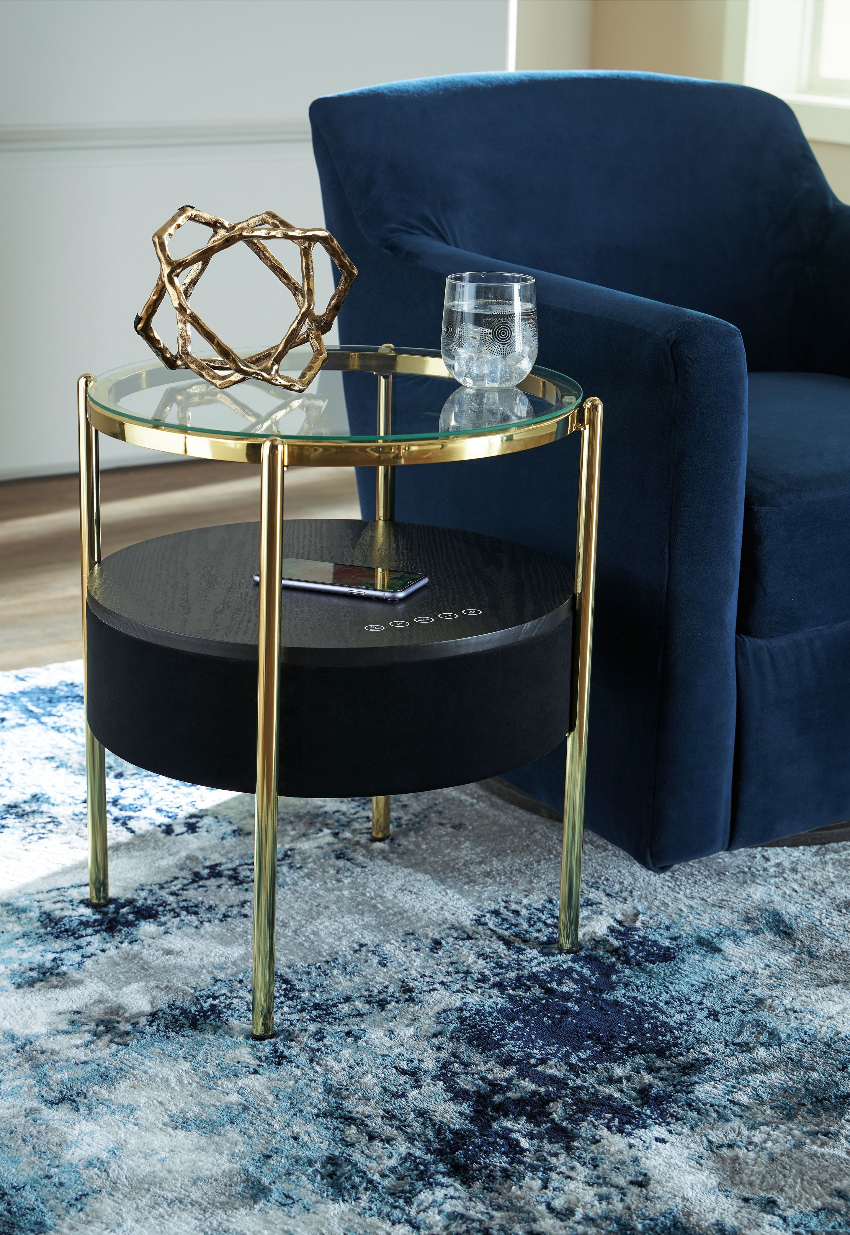 Accent table with speaker, round clear glass top over black speaker base, gold frame