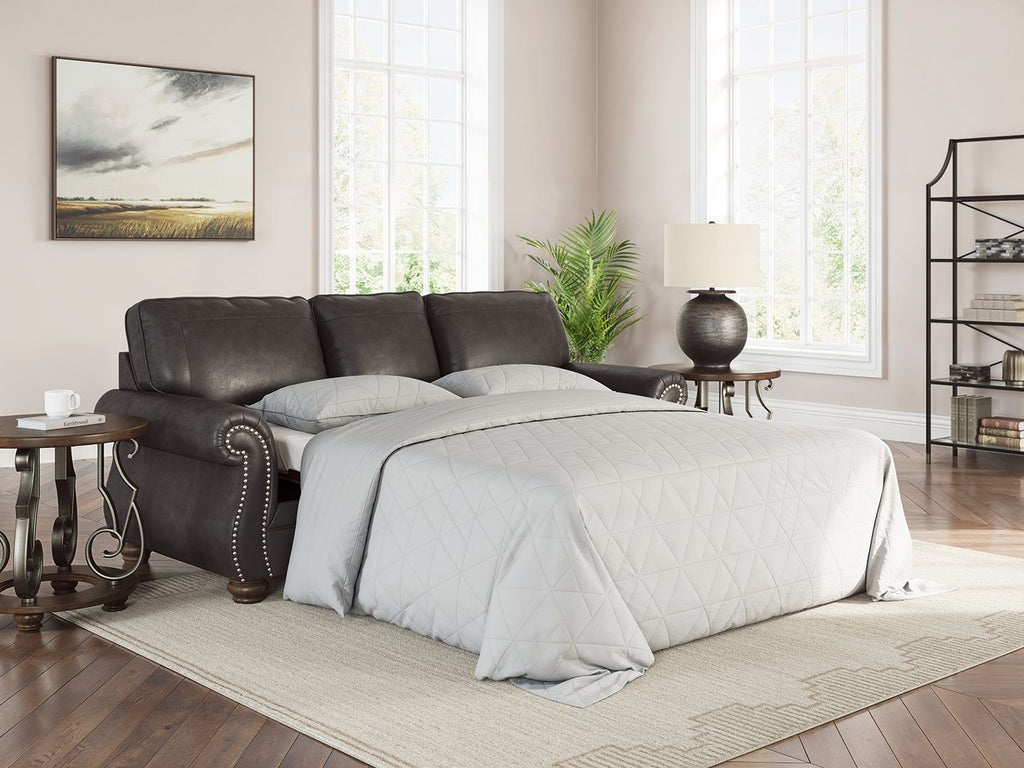 Dark gray sofa sleeper with pull-out mattress and two patterned throw pillows